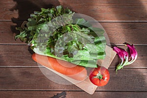 Healthy food vegetable red lettuce and romaine tomato carrot in cutting board on wood table, top view, copy space