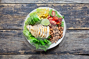 Healthy food, Vegetable salad with chicken and almond in a white plate on a wooden table. Top view