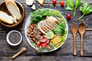 Healthy food, Vegetable salad with chicken and almond in a white plate on a wooden table. Top view