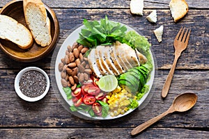 Healthy food, Vegetable salad with chicken and almond in a white plate on a wooden table. Top view