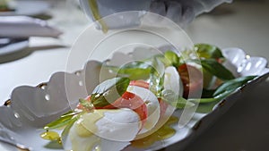 Healthy food and vegetarian concept. Close up of pouring olive oil over caprese salad. Italian caprese salad with