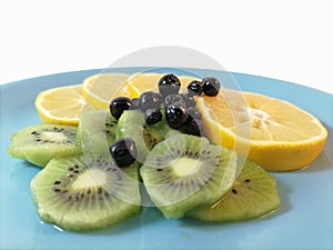 Healthy food. Vitamin bomb. Lemon  kiwi  chokeberry and blueberry on a plate. Lots of vitamins and antioxidants.