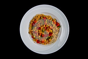 Healthy food. White rice, avocado, cherry tomatoes, green peas and hazelnuts white plate isolated on black background