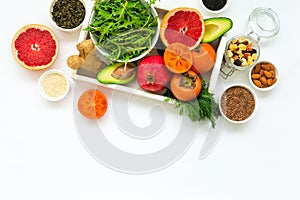 Healthy food in wooden tray: fruits, vegetables, seeds and greens on white background