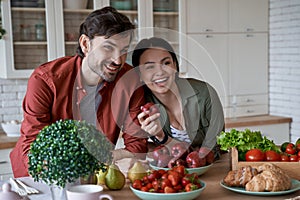 Healthy food. Young beautiful family couple, husband and wife standing in the modern kitchen at home and smiling