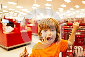 Healthy food for young family with kids. Boy at grocery store or supermarket. Portrait of funny little child holding