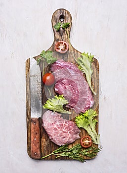 Healthy foods, cooking concept Fresh pork steak with salad, tomato with a knife for meat vintage old cutting board on a white