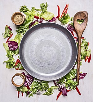 Healthy foods, cooking and vegetarian concept lettuce with a wooden spoon, salt and pepper, laid out around pan place for text