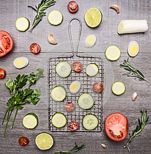 Healthy foods, cooking and vegetarian concept sliced cucumbers, zucchini, onion, lettuce, rosemary, tomatoes, parsley on wooden ru