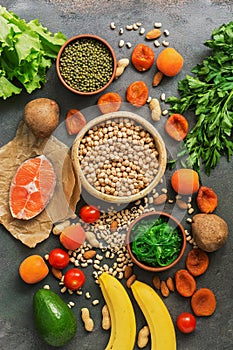 Healthy foods high in potassium. A variety of legumes, salmon, fruits, vegetables, dried apricots, seaweed chuka and nuts on a