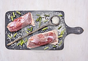 Healthy foods two raw duck breast with rice and wooden spoon for the rice on a cutting board wooden rustic background top view