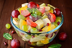 Healthy fresh fruit salad in glass bowl on wooden background.