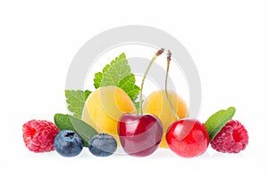 Healthy fresh fruits. Composition of ripe red sweet cherry with horns, raspberries, apricots and blueberries with leaves isolated