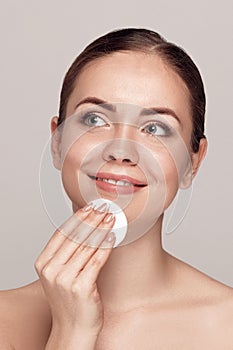 Healthy fresh girl removing makeup from her face with cotton pad. Beauty woman cleaning her face with cotton swab pad isolated on