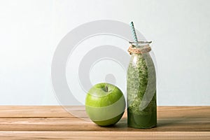Healthy fresh green smoothie juice in the glass bottle on wooden table for healthy detox and diet habits concept