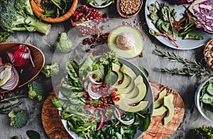 Healthy fresh salad with avocado, greens, arugula, spinach, pomegranate in plate over grey background. Healthy vegan food,