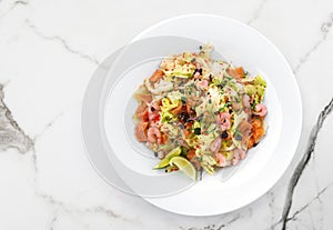 Healthy fresh salad with lettuce, greens, red caviar, shrimp, fillet salmon in plate on light marble background. Healthy food,