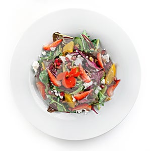 Healthy fresh salad with mix greens, strawberry, orange, nuts, cream cheese and edible flowers in plate on isolated white