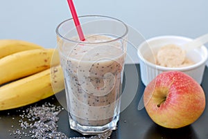 Healthy fresh smoothie drink from red apple, banana chia seeds and plant protein powder in the glass with straw