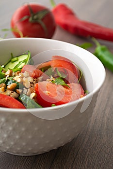 Healthy fresh summer salad with cucumbers, tomatoes, fresh arugula, chopped walnuts, pepper, olive oil and lemon juice