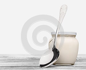 Healthy fresh yogurt with spoon on background