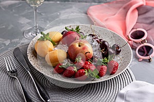 Healthy fruit platter, strawberries, apples, peaches, apricots on a dark gray wooden table, top view, close-up