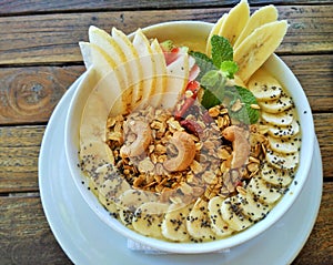 Healthy fruit smoothie bowl topped with fresh bananas, Asian pear, cashews, chia seeds, granola and mint