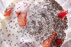 Healthy fruits smoothies with shia seeds and strawberries in blender, close up. Flat lay