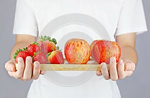 Healthy fruits with strawberries and apples holding by man with white T Shirt