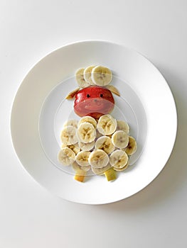 Healthy and fun food for kids, banana and apple lamb, on white plate