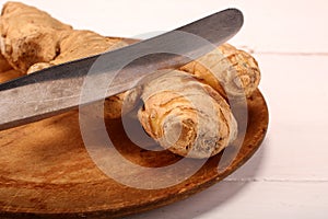 Healthy ginger root on cutting board and knife. Isolated on white background