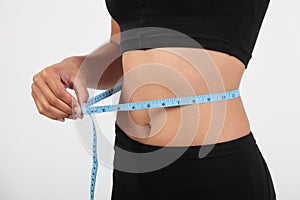 Healthy girl checking waist size with tape measure