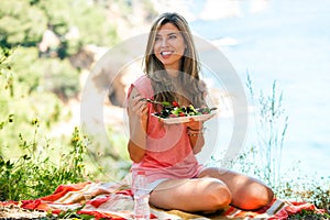 Healthy girl having salad at picnic.