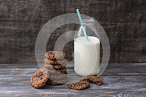 Healthy gluten-free buckwheat cookies with chocolate and bottle of milk on wooden table