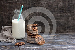 Healthy gluten-free buckwheat cookies with chocolate and bottle of milk on wooden table