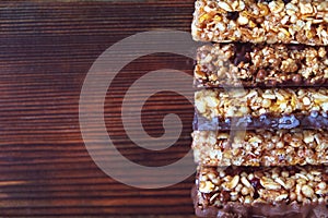 Healthy granola bars with dried fruits, nuts and honey on wooden background.