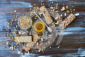 Healthy granola bars with dried fruits, nuts and honey on wooden background.