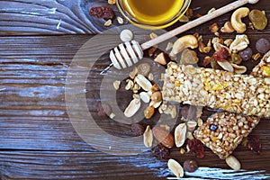 Healthy granola bars with dried fruits, nuts and honey on wooden background.