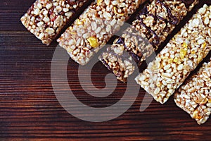 Healthy granola bars with dried fruits, nuts and honey on wooden background.