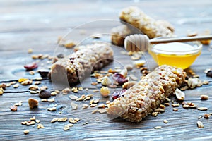 Healthy granola bars with dried fruits, nuts and honey on wooden background.