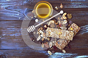 Healthy granola bars with fruits, nuts and honey on wooden background.