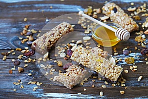 Healthy granola bars with fruits, nuts and honey on wooden background.