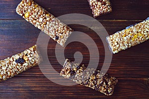 Healthy granola bars with fruits, nuts and honey on wooden background.