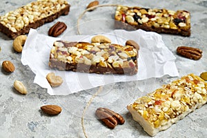 Healthy granola bars with nuts, seeds and dried fruits on the gray texture table, with copy space.