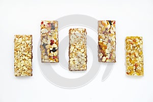 Healthy granola bars with nuts, seeds and dried fruits on white baking paper. Top view.