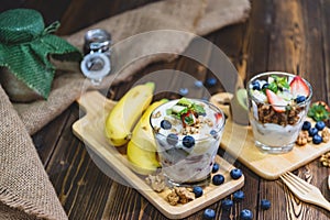 Healthy Greek yogurt with Granola and mixed berries on wooden table and many fruits. Food and dessert concept