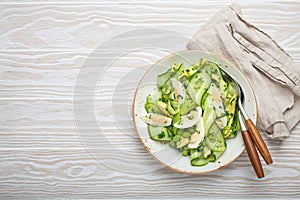 Healthy green avocado salad bowl with boiled eggs, sliced cucumbers, edamame beans, olive oil and herbs on ceramic plate