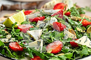Healthy Green Salad Leaves, Slices of Fresh Strawberries. Concept healthy and balanced eating. Food recipe background