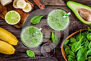 Healthy green smoothie with banana, lime, spinach, avocado and chia seeds in glass jars