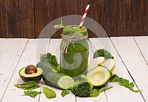 Healthy green smoothie with banana, spinach, avocado and cucumber in a glass bottles on a rustic